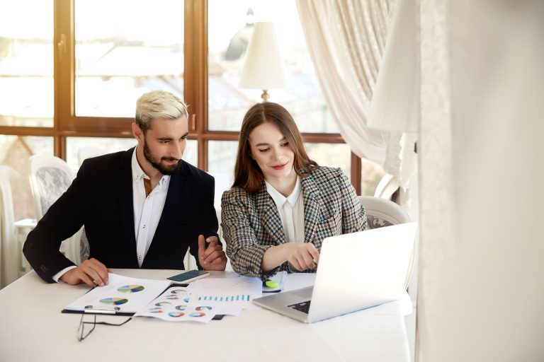 Young blonde man and brunette woman are looking at the computer